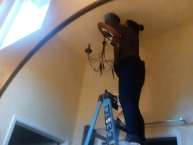 Electrician installing a chandelier in a Fairfax residence